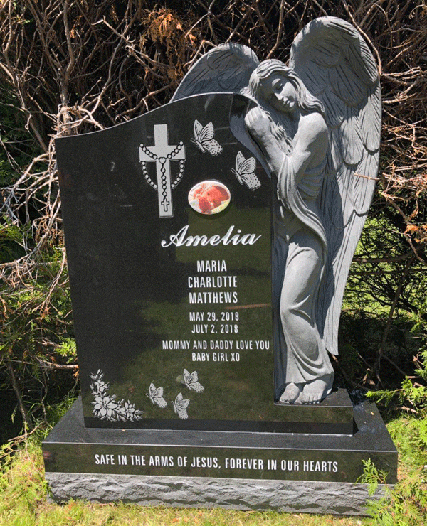 Black granite memorial headstone with a sculpted angel, engraved butterflies, a rosary cross, and a portrait medallion