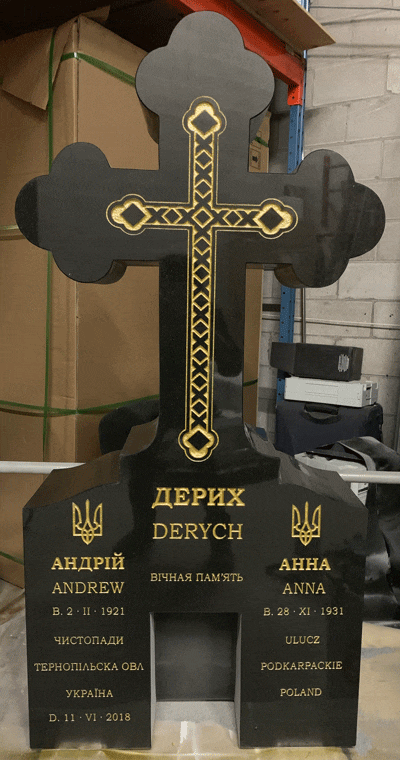 Black granite cross-shaped monument with a gold-inlaid ornate cross and Ukrainian emblems