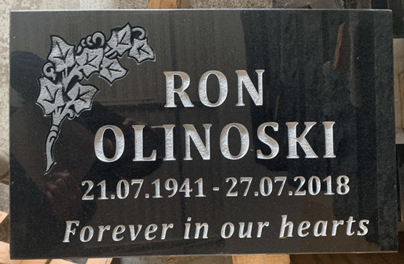 Black granite flat grave marker with a carved ivy-leaf corner