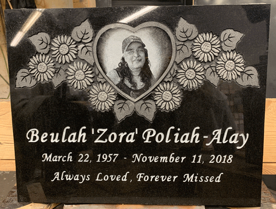 Black granite flat grave marker with carved sunflowers and a heart-shaped laser-etched portrait