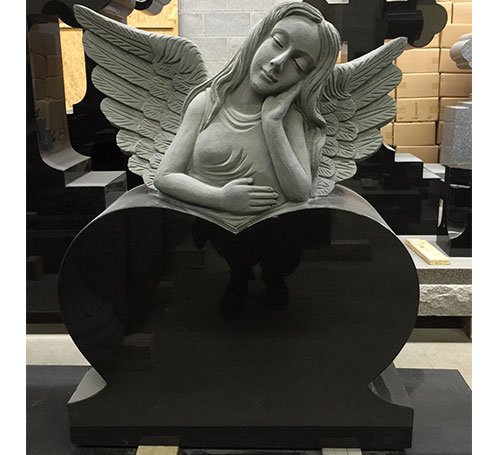Grey granite carved angel resting on a black granite heart