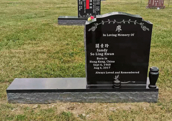 Black granite serpentine-top headstone with an engraved floral vine, English and Chinese inscription