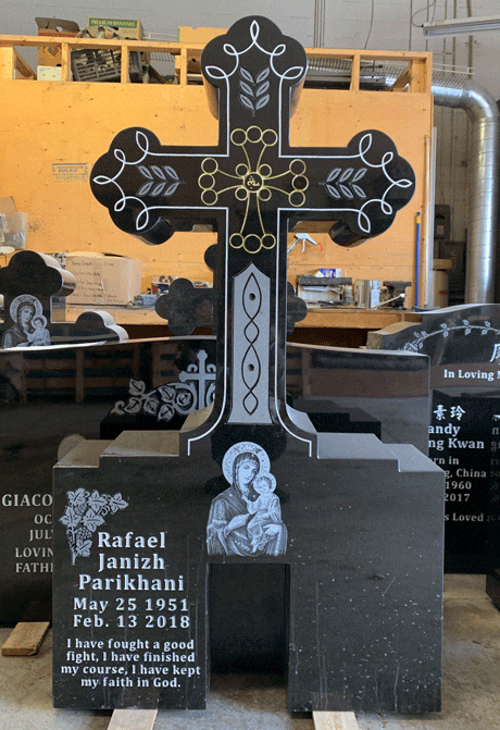 Black granite monument topped with an ornate Orthodox cross, an engraved Madonna and Child, and a rose