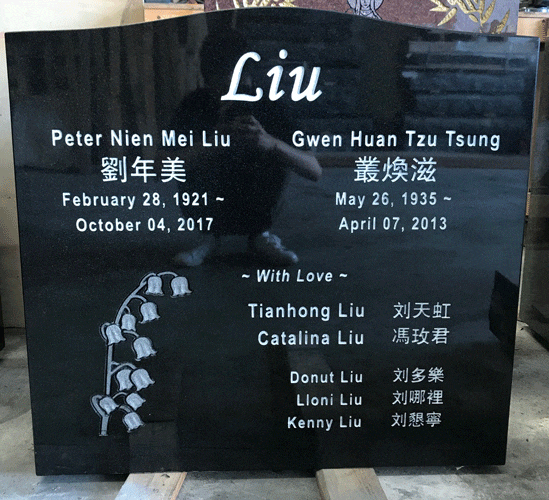 Black granite upright family headstone with an engraved lily-of-the-valley spray and English and Chinese names