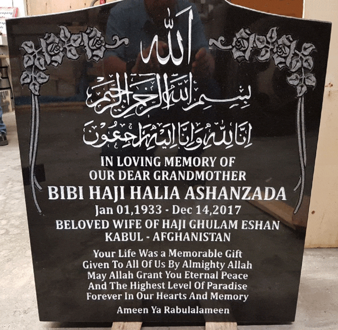 Black granite upright headstone with carved rose corners and engraved Islamic calligraphy with English inscription