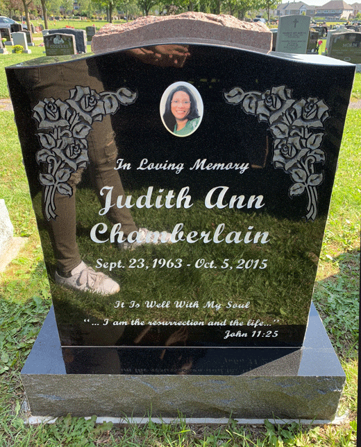 Black granite upright headstone with carved rose corners and a portrait medallion