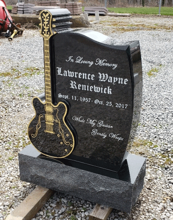 Black granite upright headstone with a carved gold-inlaid electric guitar