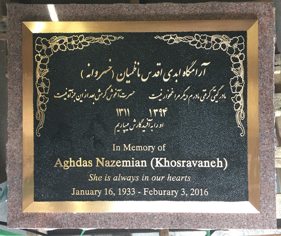 Bronze memorial marker with Arabic script and floral corners