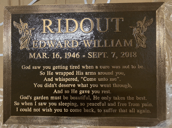 Bronze memorial plaque with floral border and inscription