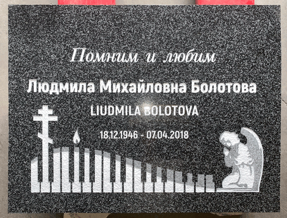 Black granite flat grave marker with an engraved Orthodox cross, candle, piano keys, and a kneeling angel, Russian inscription