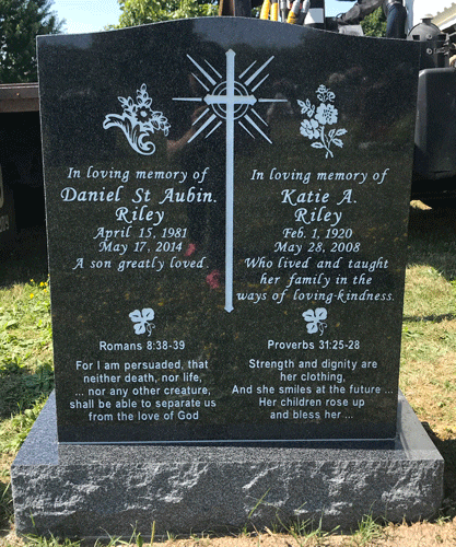 Dark grey granite upright companion headstone with an engraved radiant cross and floral motifs