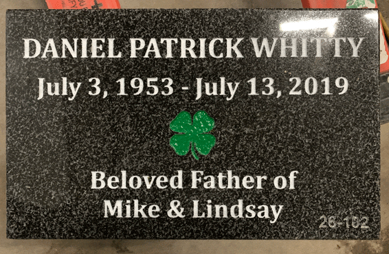 Dark granite flat grave marker with a painted four-leaf clover