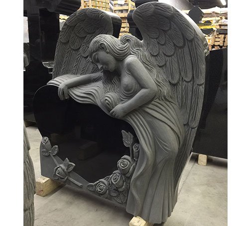 Grey granite carved angel embracing a black granite heart with roses