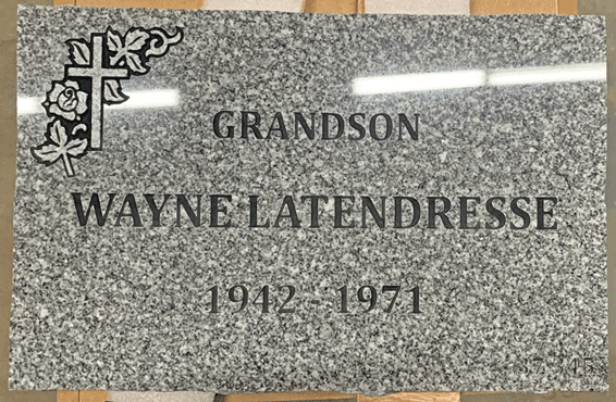 Grey granite flat grave marker with a carved cross and rose