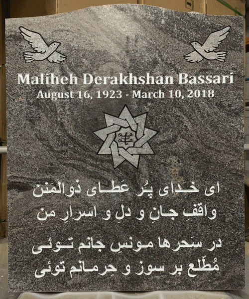 Grey granite upright headstone with two engraved doves and a Baha'i nine-pointed star, Persian inscription