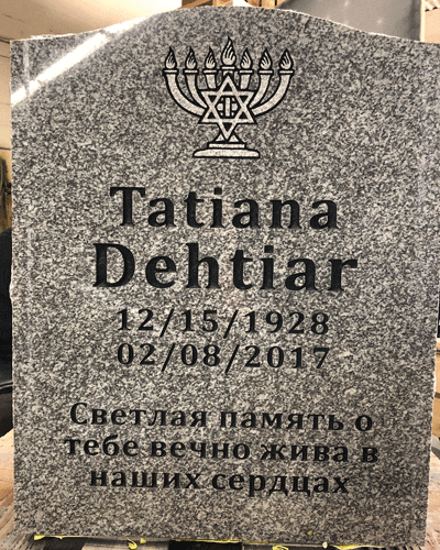 Grey granite upright headstone engraved with a menorah and Star of David