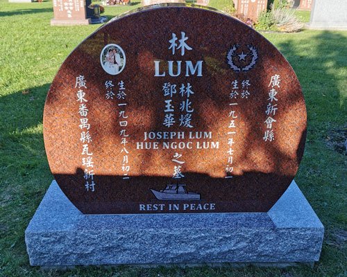 Red granite round-top upright headstone with a ceramic portrait, an engraved boat, and English and Chinese inscription