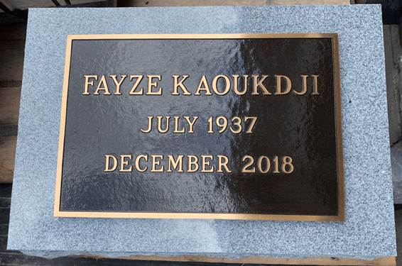 Simple bronze grave marker on light gray granite base