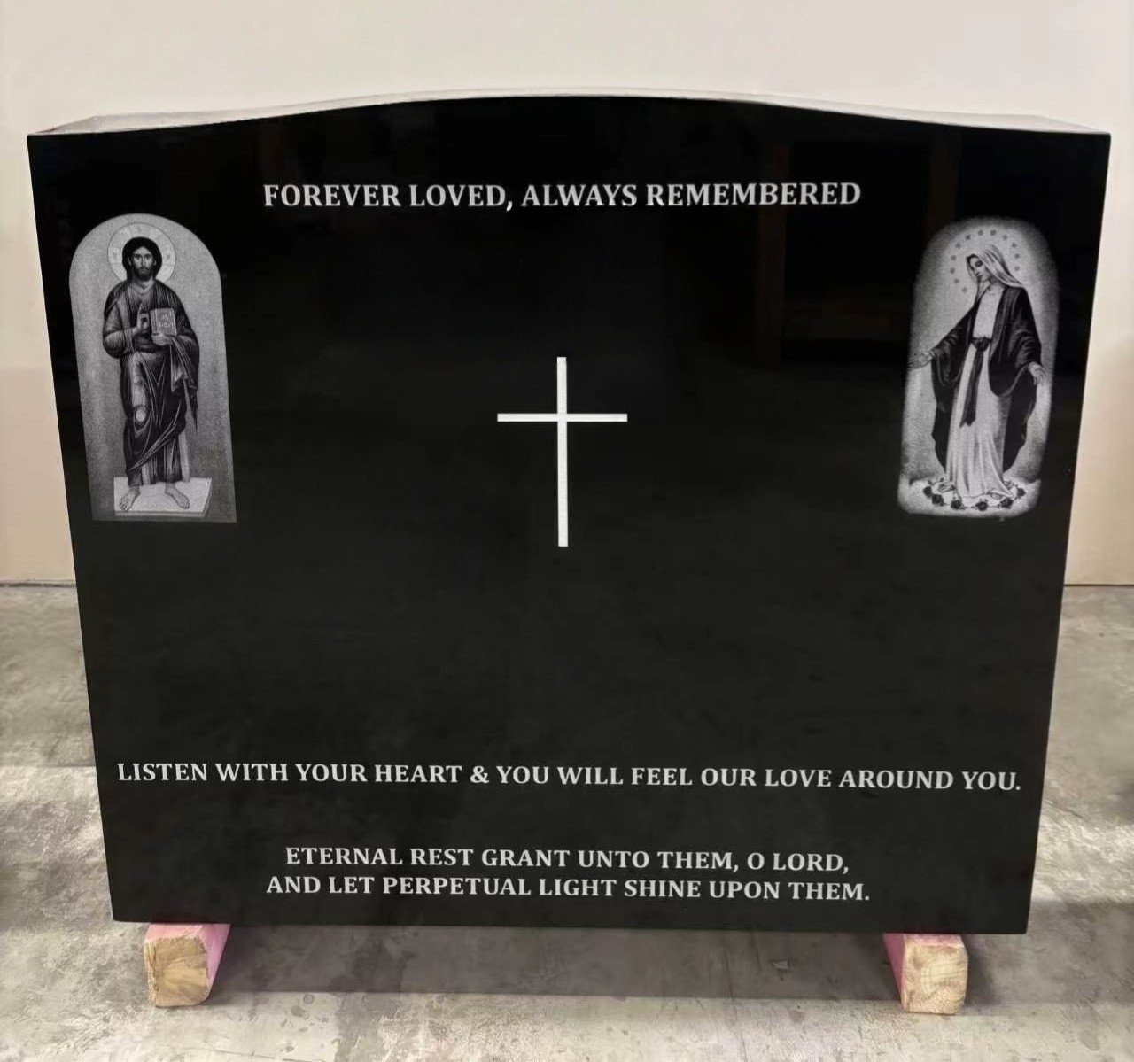 Finished black granite headstone with the Christ and Virgin Mary portraits laser-etched into the polished stone
