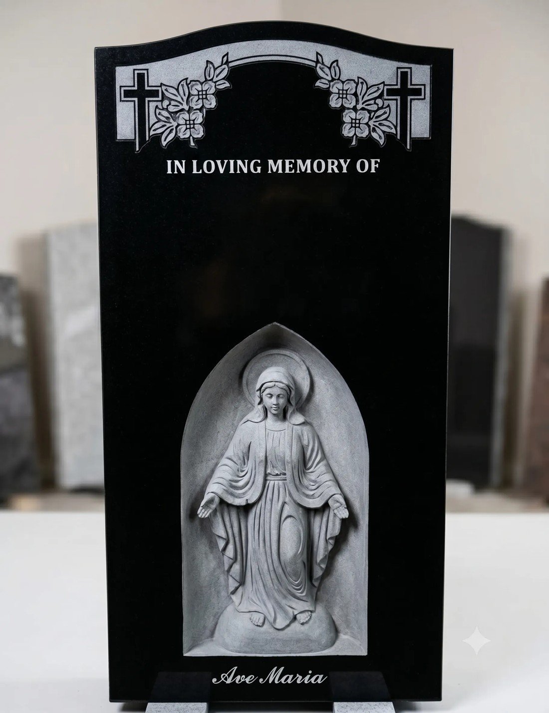 Deep three dimensional relief carving of the Madonna in an arched niche on a black granite monument