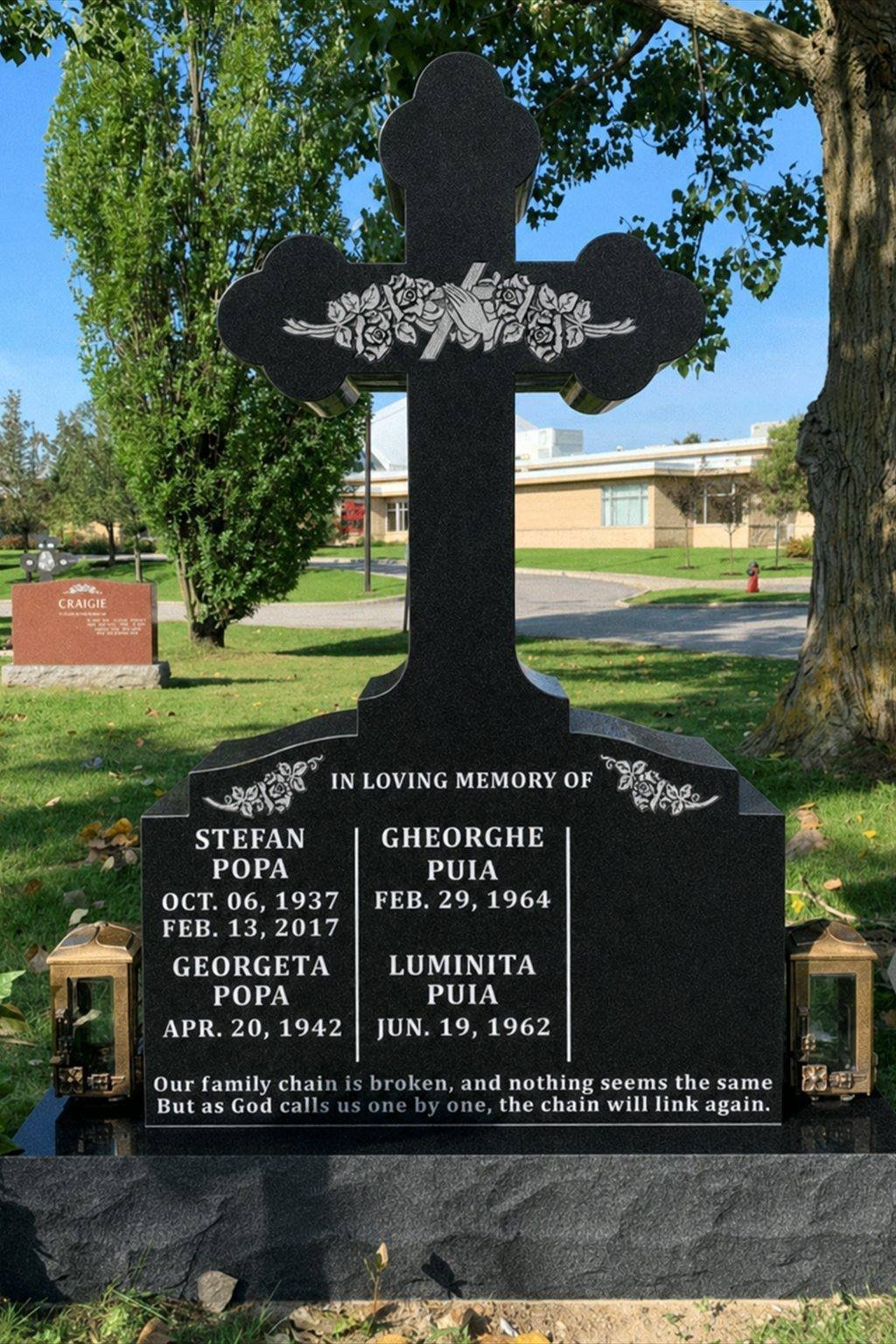 Black granite cross-shaped family monument with carved roses and praying hands