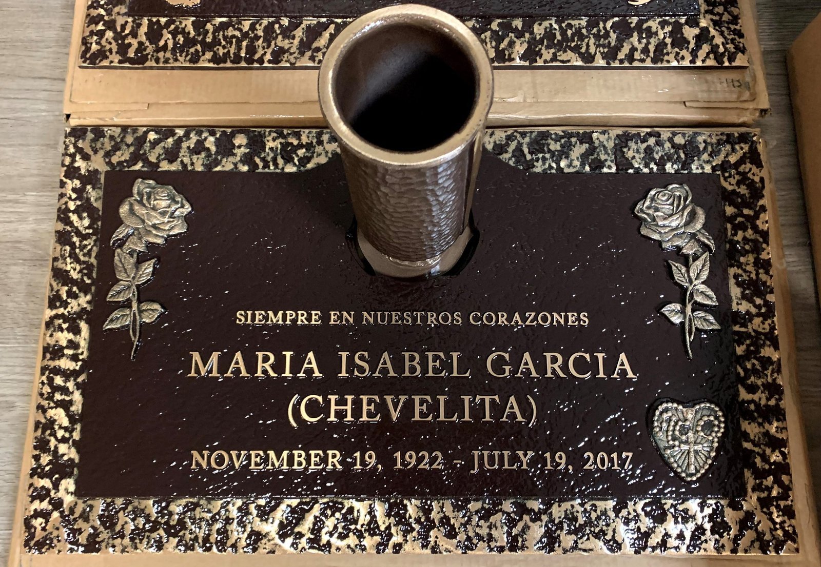 Bronze marker with vase floral corners and Mary emblem