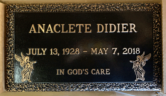 Bronze memorial marker with praying hands and wheat border