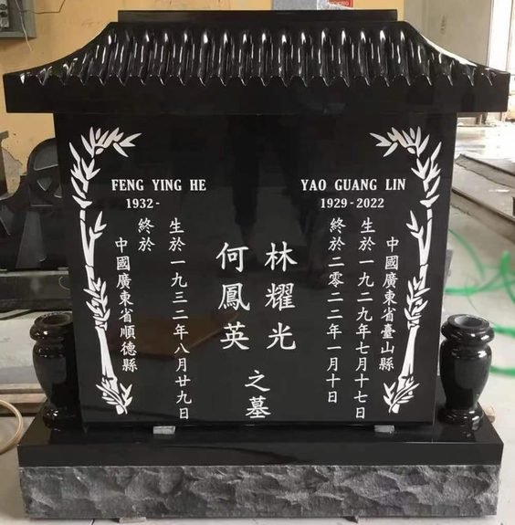 Black granite pagoda monument with carved bamboo and vertical Chinese columns