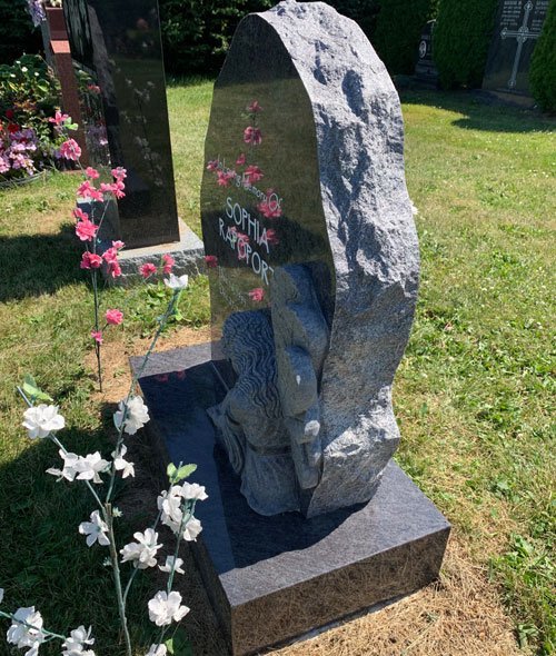 Side view of gray angel headstone with wing carving