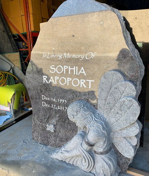Gray granite angel headstone with kneeling figure and wings