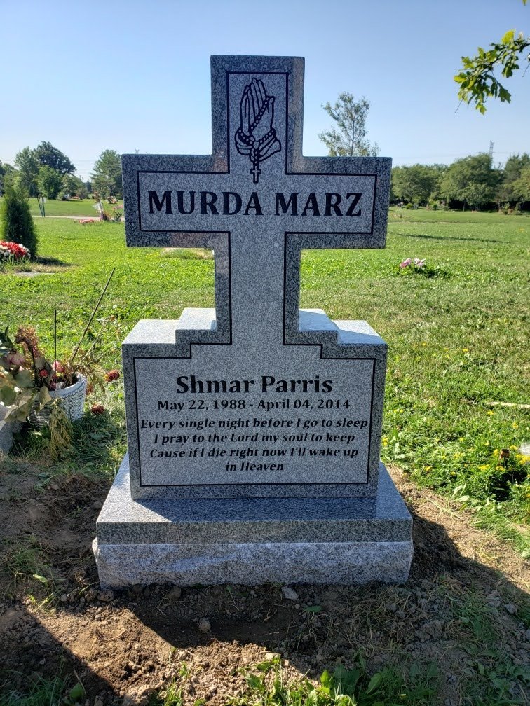 Light Grey granite cross shaped headstone with carved praying hands and rosary