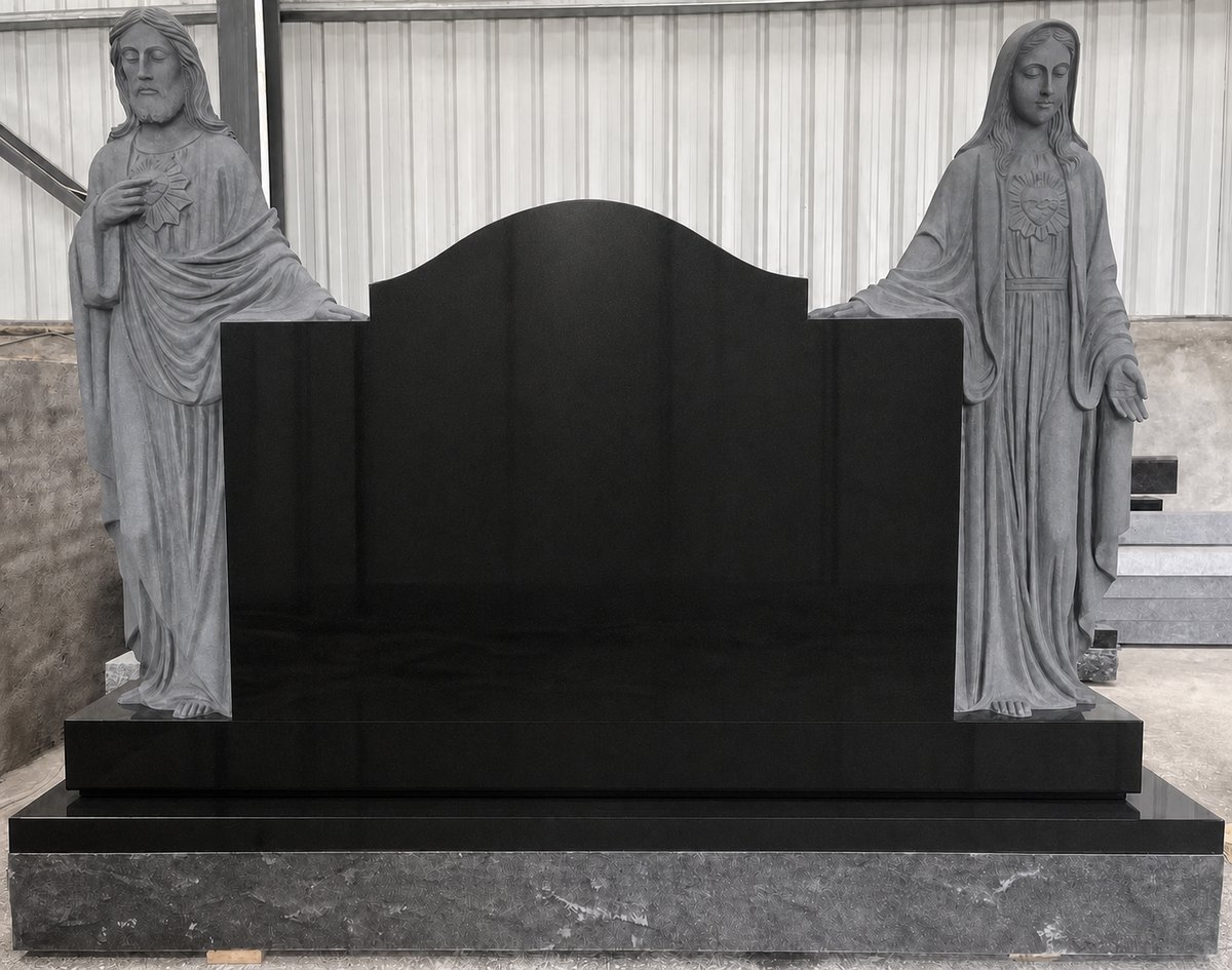 Black granite statue monument with carved Jesus and Mary statues beside a tablet