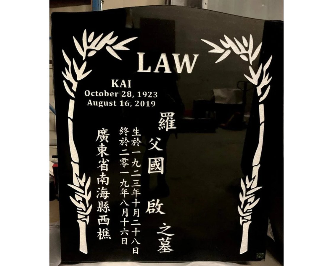 Black granite monument with carved bamboo borders framing vertical Chinese columns