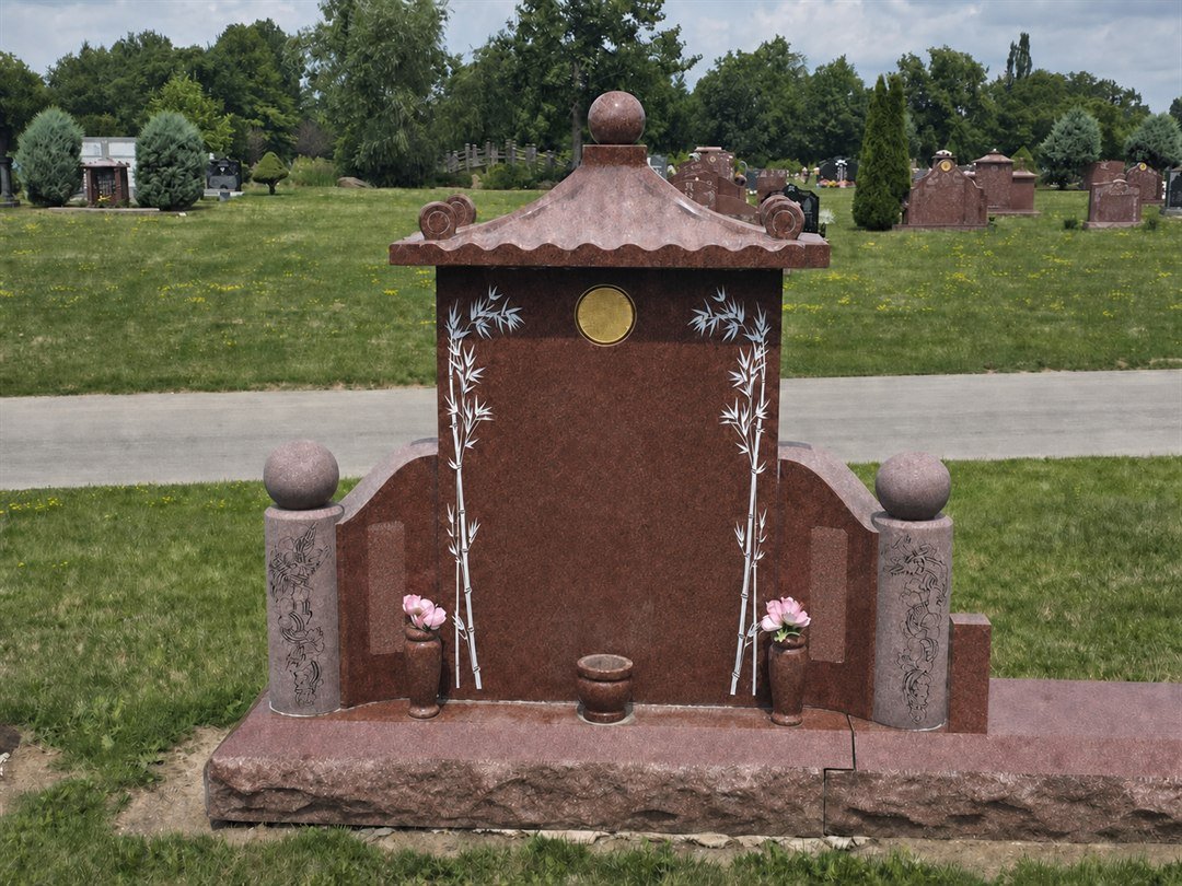Red granite Chinese style monument with a roof resting on the tablet, a ball finial at the peak and bamboo motifs