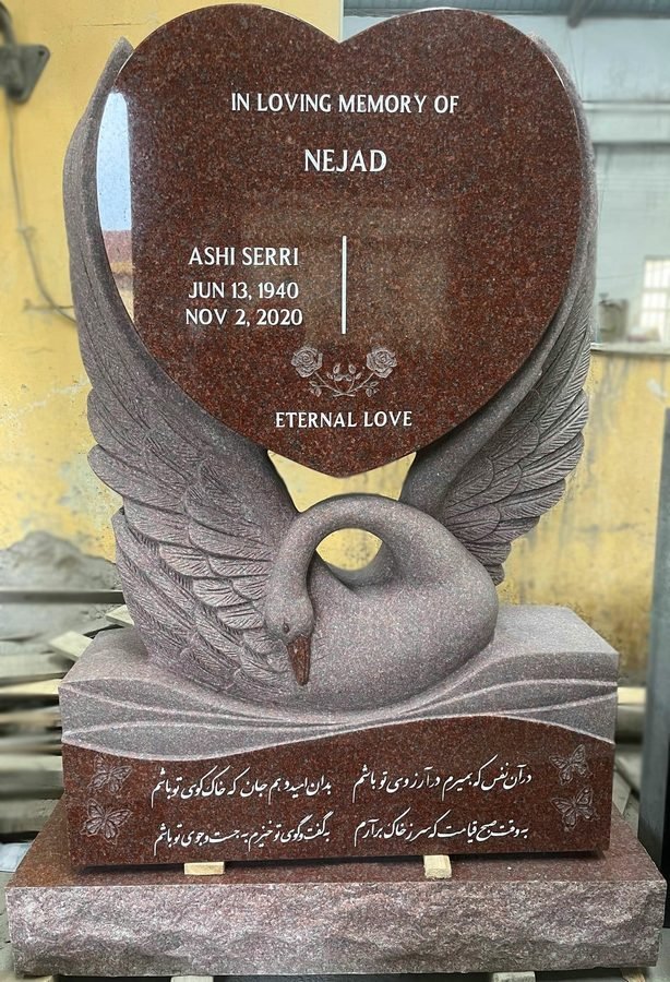 Indian Red granite heart shaped headstone carried by a carved swan
