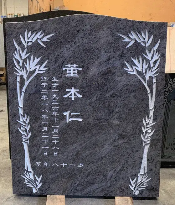 Bahama Blue granite serpentine top headstone with carved bamboo borders