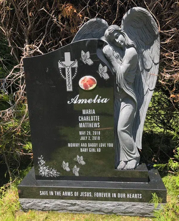 Black granite memorial headstone with a sculpted angel, engraved butterflies, a rosary cross, and a portrait medallion