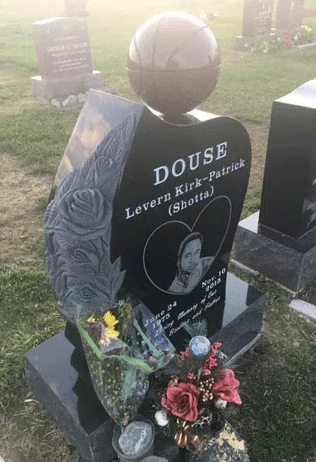 Black granite headstone with a basketball sphere on top, a carved angel wing with roses and a heart shaped etched portrait