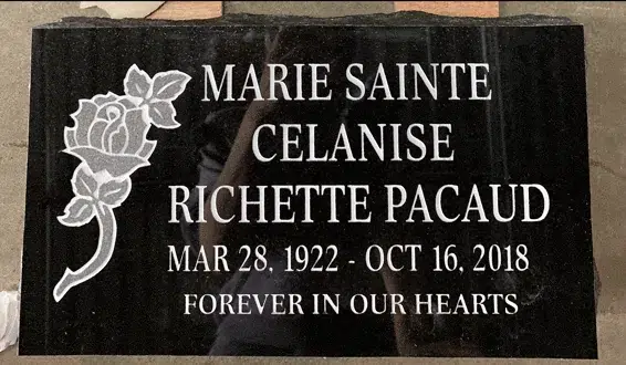Black granite flat grave marker with a carved rose at the left, a name in large lettering, dates and a short epitaph