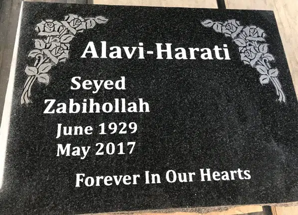 Black polished granite flat marker with rose sprays in both upper corners, a family name, given names, dates and an epitaph