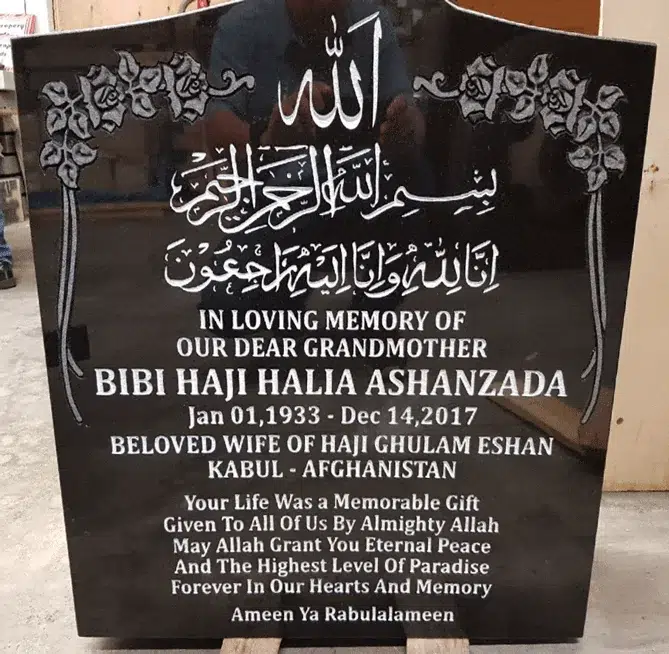 Black granite arched top headstone with engraved rose corners, Arabic calligraphy and an English memorial inscription