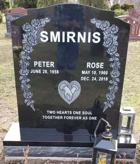 Black granite ogee top headstone with etched rose vines on both sides and clasped hands inside a heart above an epitaph