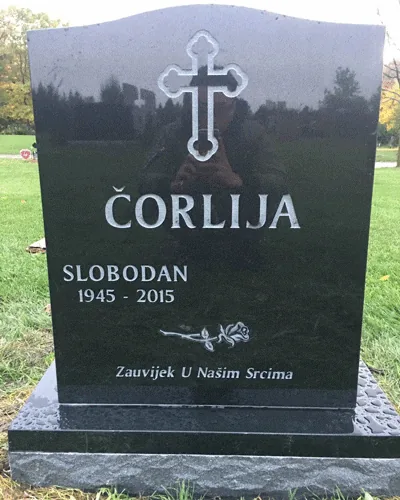 Black granite serpentine top headstone with an engraved trefoil cross, a single rose, a surname and an epitaph
