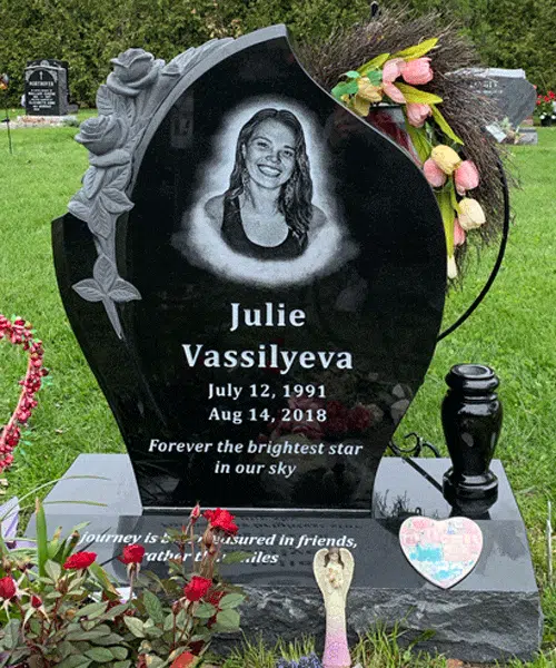 Black granite teardrop shaped headstone with carved roses on one side, a laser etched portrait, name and dates and a vase