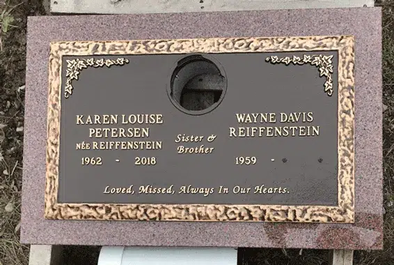 Bronze companion marker with a center vase, rose corners and an ornate border on a pink granite base, two names and dates