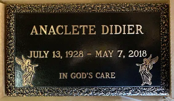 Bronze flat marker with a textured border, raised name, dates and epitaph, and an angel figure in each lower corner