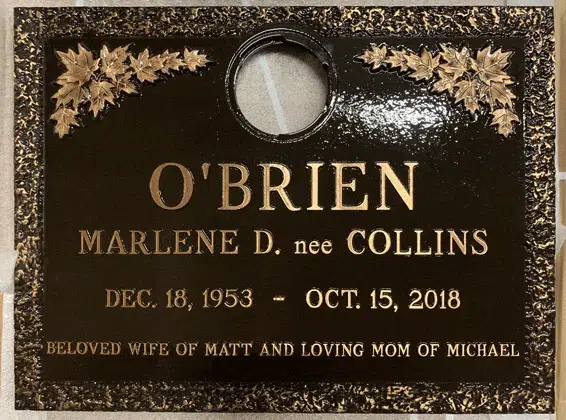 Bronze grave marker with maple leaf clusters in the upper corners, a round vase opening and a rough textured rim