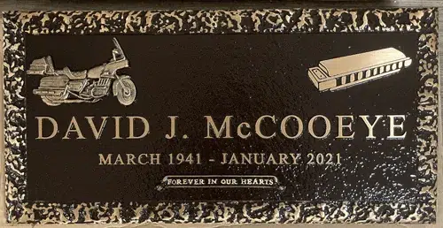 Bronze flat marker with a dark background, mottled border, raised lettering and touring motorcycle and harmonica emblems