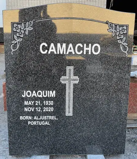 Dark Brits granite serpentine top headstone with Latin cross and floral corner scrolls
