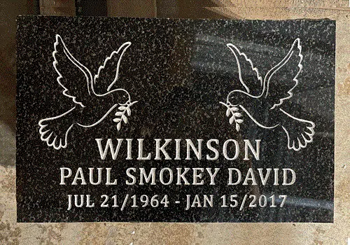 Dark Brits granite flat grave marker engraved with two doves carrying olive branches above a name and dates